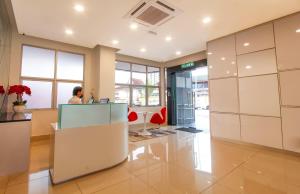 un hombre sentado en un escritorio en el vestíbulo de una oficina en CitiVilla Hotel Penang, en George Town