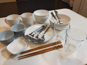a white table with chopsticks and plates and glasses on it at 龍馬坂荘：1日1組限定・東山清水のてっぺんの小さなお宿、わんこと一緒に。 in Kyoto