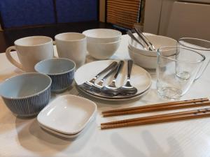 a table with white dishes and chopsticks on a table at 龍馬坂荘：1日1組限定・東山清水のてっぺんの小さなお宿、わんこと一緒に。 in Kyoto