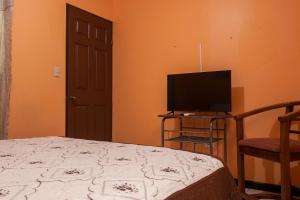 a bedroom with a bed and a flat screen tv at Marta's Guesthouses, apartamentos con entrada autonoma in Puerto Limón