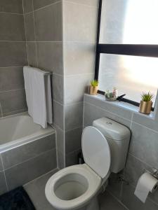 La salle de bains est pourvue de toilettes blanches et d'une baignoire. dans l'établissement Sarona City L203, à Gaborone