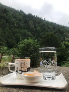 a glass jar and a cup on a plate with a drink at FERAH BUTİK OTEL in Çamlıhemşin
