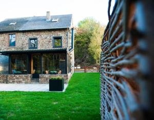 een stenen huis met een hek in de tuin bij GITE AU BORD DE L'AISNE in Érezée