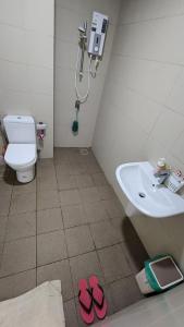 a bathroom with a sink and pink slippers on the floor at Anggun I Soho I City Homestay in Shah Alam