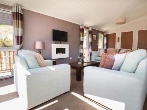 sala de estar con 2 sillas blancas y mesa en 23 Bossiney Bay, en Tintagel