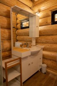 ein Badezimmer in einem Blockhaus mit einem Waschbecken und einem Spiegel in der Unterkunft Les Flocons de Neige in Bolquere