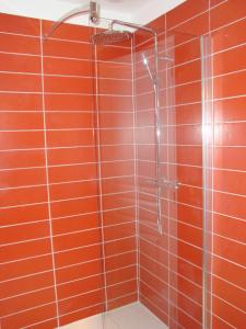 y baño con ducha y azulejos de color naranja. en Les Ecureuils en Bougligny