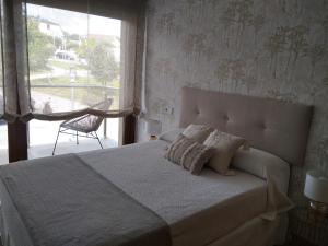 a bedroom with a bed with pillows and a window at Chalet con vista a las Islas Cíes in Sanxenxo