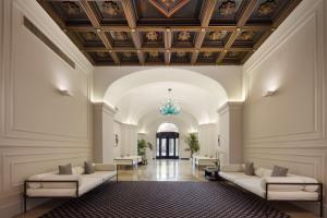 a lobby with couches and a ceiling with a chandelier at Patria Palace Lecce - The Leading Hotels of The World in Lecce