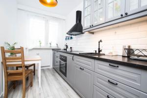 a kitchen with white cabinets and a sink and a table at WAW Apartamenty Cybernetyki in Warsaw