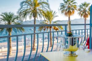 a bottle of champagne on a table on a balcony with palm trees at Bel Appartement Face à La Mer Près Du Centre - Le Voilier in Cannes