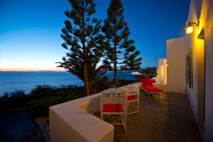 a patio with a table and chairs and the ocean at AEGEAN in Mikonos