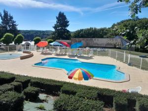 een zwembad met een parasol en parasols bij VVF Lac d'Eguzon in Éguzon-Chantôme