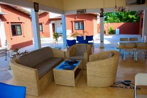 un patio con muebles de mimbre, mesa y sillas en RESIDENCE AINA, en Abomey-Calavi