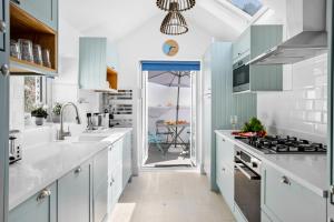 a kitchen with white counters and blue cabinets at The Captain's Cottage, Brixham in Brixham
