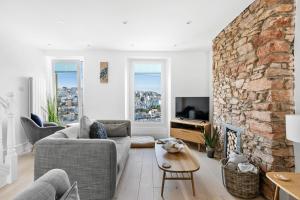 a living room with a couch and a stone fireplace at The Captain's Cottage, Brixham in Brixham