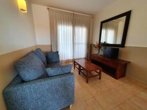 sala de estar con sofá azul y mesa en Apartamentos Las Dunas-B, en Riumar