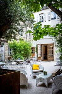 Les Remparts Hôtels et Demeures Historiques في بون: فناء فيه كراسي وطاولات ومخدة صفراء
