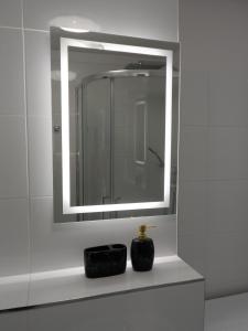 een badkamer met een spiegel en een zwarte zeepdispenser bij Turkusowy Zakątek Głogów in Głogów