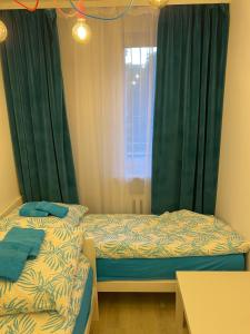 2 łóżka w pokoju z zielonymi zasłonami i oknem w obiekcie Turkusowy Zakątek Głogów w Głogowie