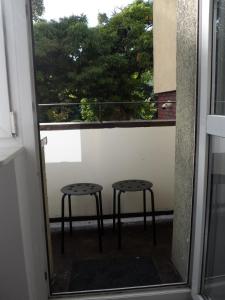 ein Paar Hocker auf einem Balkon mit einem Fenster in der Unterkunft Turkusowy Zakątek Głogów in Głogów