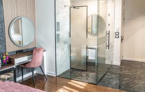 y baño con ducha de cristal, escritorio y silla rosa. en 9 Nine - Luxury Apartments & Suites, en Belgrado