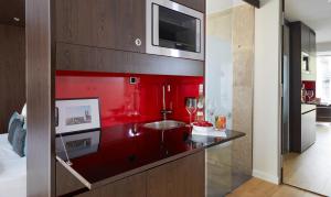 a kitchen with a red wall with a sink at Living Hotel Das Viktualienmarkt in Munich