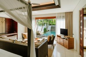 ein Wohnzimmer mit Fernseher und ein Wohnzimmer mit Pool in der Unterkunft The Samaya Seminyak Bali in Seminyak