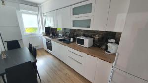 eine Küche mit weißen Schränken und einer Theke mit einer Mikrowelle in der Unterkunft Aparthotel Junior4 Cluj in Cluj-Napoca