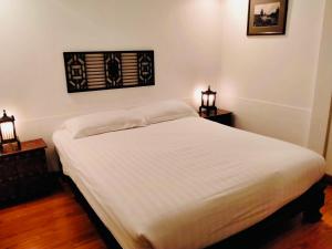 a white bed in a room with two night stands at BTC Hua Hin Home managed by BTC Boutique Resort in Hua Hin
