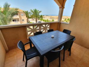 una mesa y sillas en un balcón con vistas en Apartamentos Las Dunas-B en Riumar