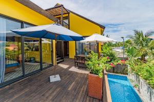 a deck with two umbrellas and a swimming pool at May Villa 6BR Beachfront An Bang Beach Hoi An by Beachside Boutique Homes in An Bàn (2) +24 photos