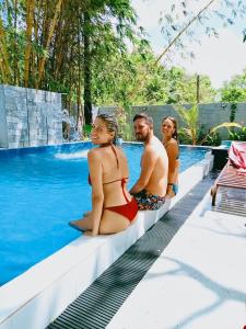 a group of people sitting on the edge of a swimming pool at Bangalawa Resort in Habarana