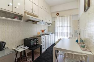 una cocina con armarios blancos, una mesa y una barra en Pagrati 2 bedrooms 5 persons apartment by MPS, en Atenas
