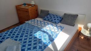 een bed met blauwe en witte lakens en kussens bij Zámor Nyaraló in Keszthely