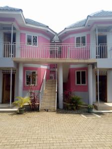 una casa rosa con una escalera delante en R&R Gardens Hotel, en Mbale