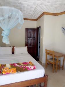 1 dormitorio con 2 camas, mesa y silla en R&R Gardens Hotel, en Mbale