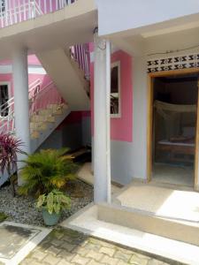 ein rosafarbenes Haus mit einer Treppe und einer Veranda in der Unterkunft R&R Gardens Hotel in Mbale