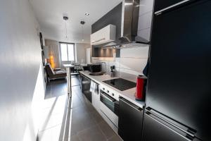 a small kitchen with a stove and a refrigerator at Théa : Studio avec parking privé - Actif+ Location- in Marseille
