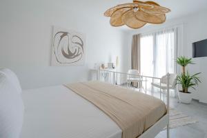 a white bedroom with a bed and a chandelier at Voger Alaçatı Köyiçi in Alacati