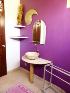 a bathroom with a bowl sink and a purple wall at Bali Oase Resort in Pemuteran