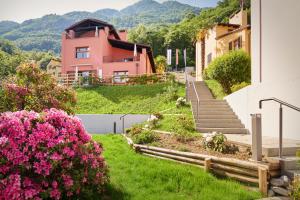 une maison sur une colline avec des fleurs roses et des escaliers dans l'établissement Reka-Ferienanlage Magadino, à Magadino