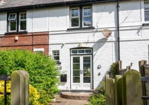 een wit huis met een witte deur en een hek bij Cookies Coastguard Cottage in New Romney