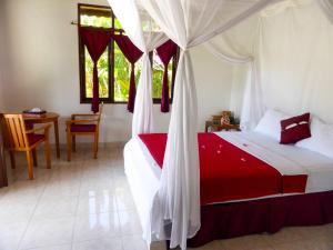 a bedroom with a bed with a red and white canopy at Bali Oase Resort in Pemuteran