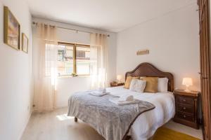 um quarto branco com uma cama grande e uma janela em Metro Lapa House with sunny balcony and A/C no Porto