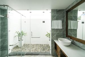 a bathroom with a shower and a sink and a mirror at DAD Resort Phú Quốc in Phú Quốc