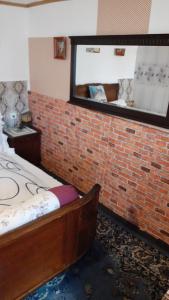 Zimmer mit Ziegelwand, Bett und Spiegel in der Unterkunft Casa Denis in Turda