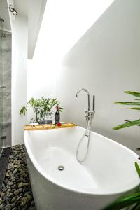 a white bath tub in a bathroom with plants at DAD Resort Phú Quốc in Phú Quốc