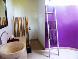 a bathroom with a large tub and purple walls at Bali Oase Resort in Pemuteran