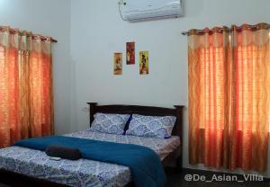 a bedroom with two beds and orange curtains at De Asian Villa Pondicherry in Auroville